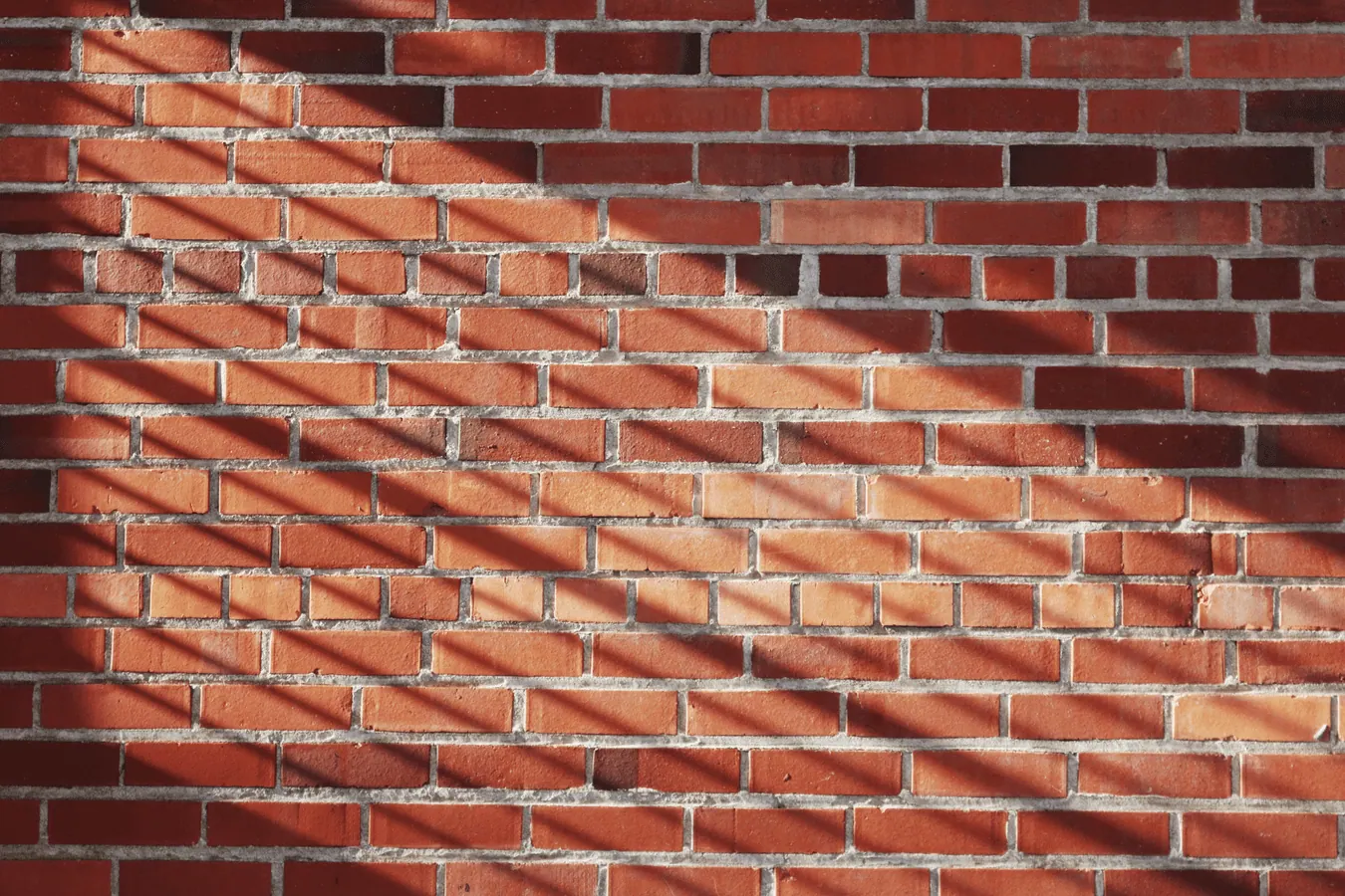 Red brick wall with clean mortar joints in sunlight