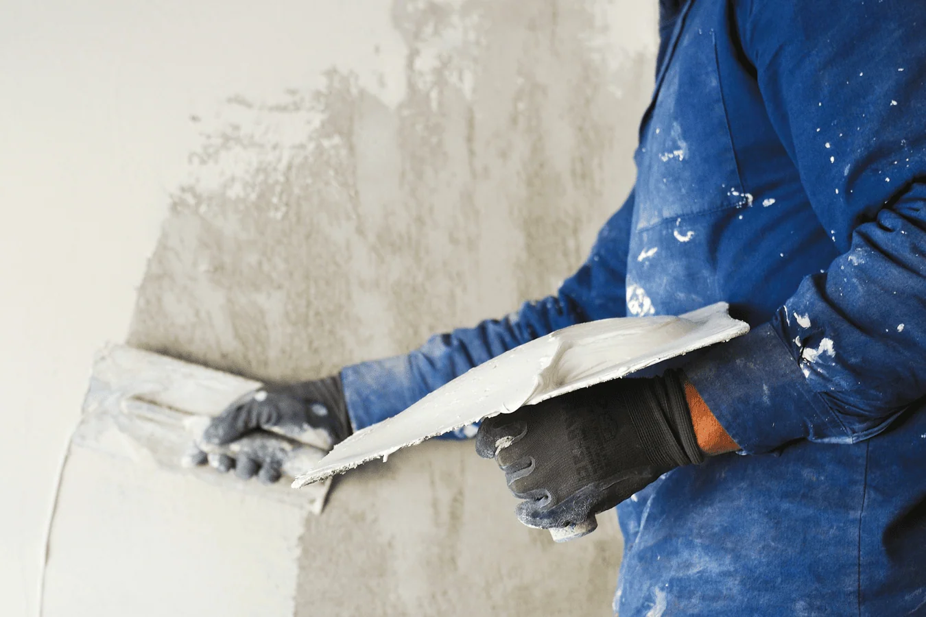 Professional plasterer applying smooth finish to interior wall