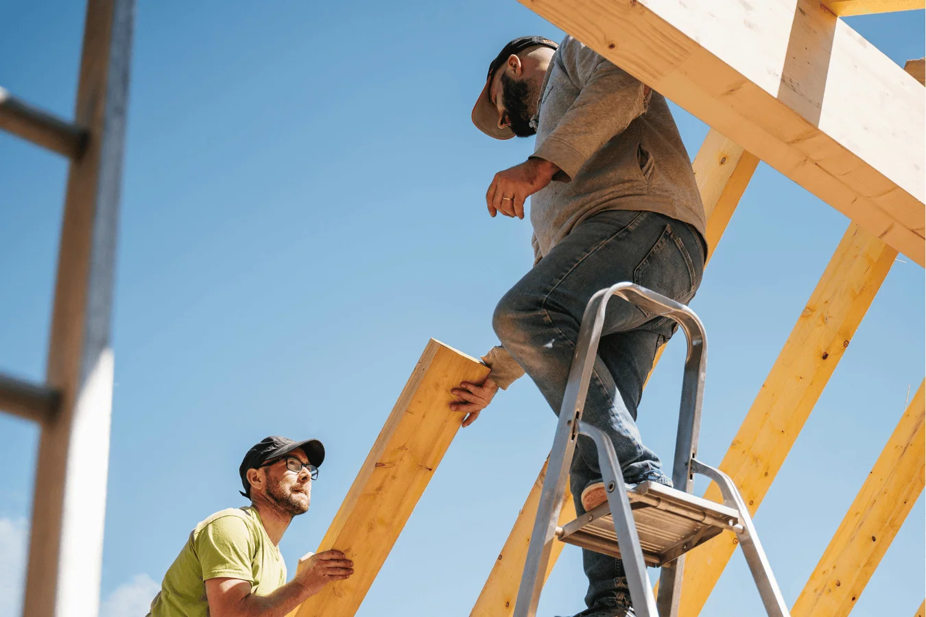 Construction workers building a wooden roof frame on a clear day